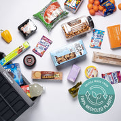 Assorted snacks and drinks on a white surface with a 'Crate made from 100% recycled plastic' logo.