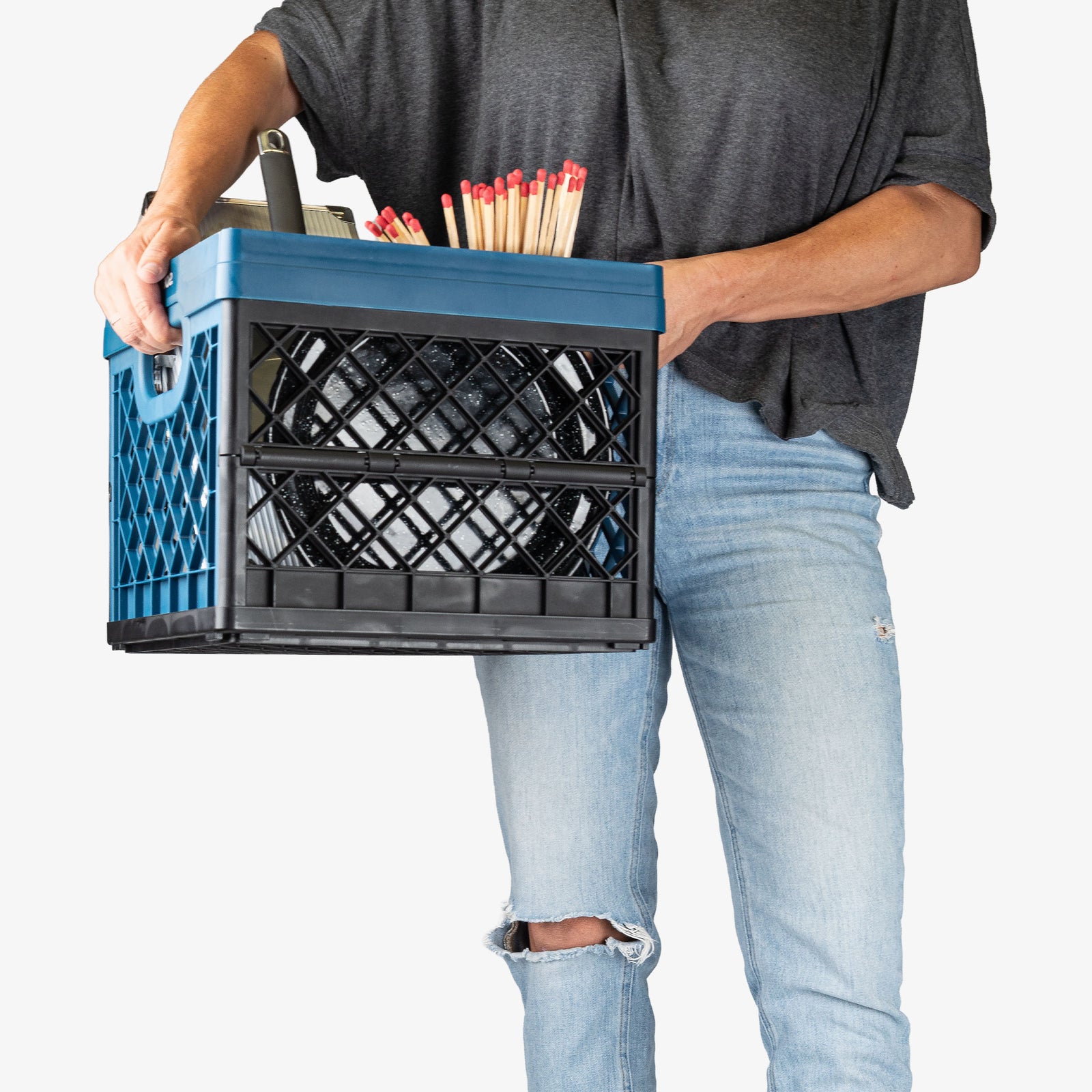 Person holding a blue crate filled with office supplies against a white background