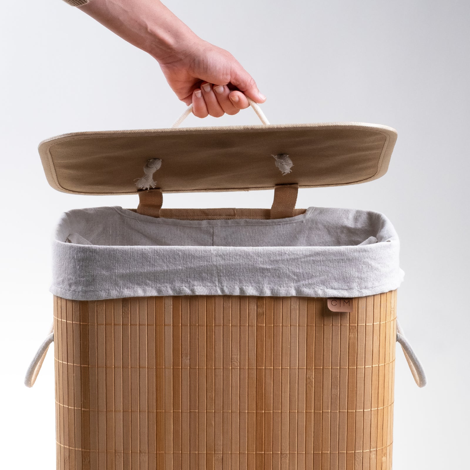 Opening cover of collapsible bamboo laundry hamper with a lid and handles, featuring a natural beige color.