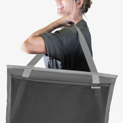Person wearing a gray collapsible tote bag with a visible brand logo on a white background