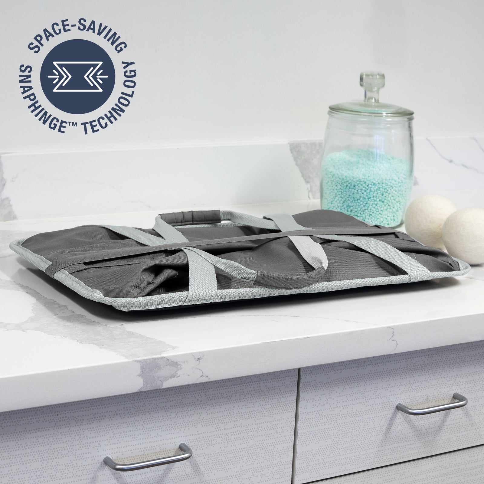 Folded gray collapsible tote MAX with straps on a kitchen counter, featuring 'Space-Saving SnapHinge Technology' logo.