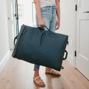 Person holding a large dark blue laundry bag in a home setting.