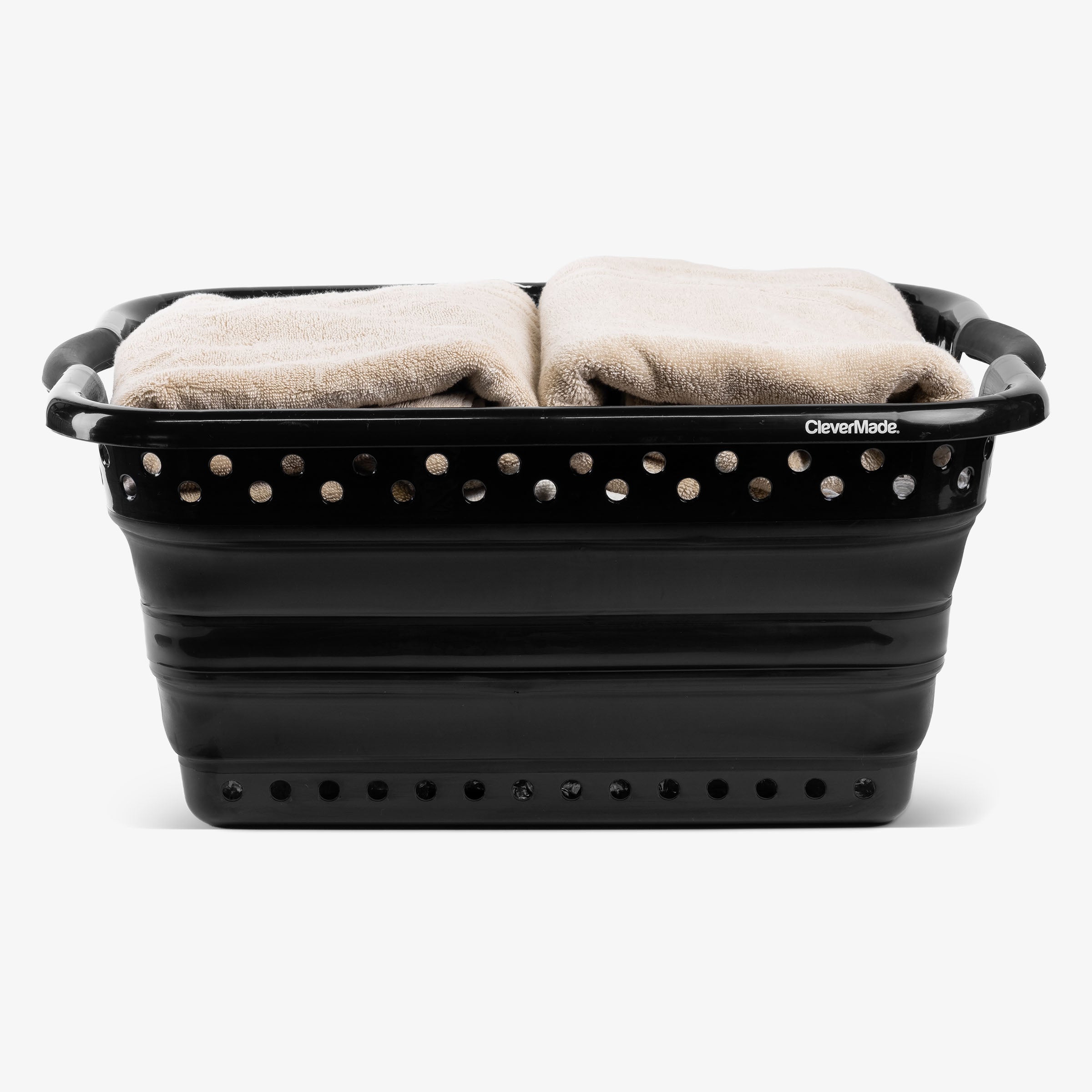 Black collapsible laundry basket with towels inside on a white background