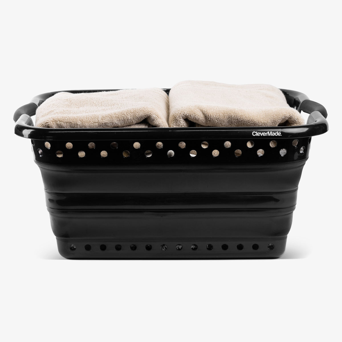 Black collapsible laundry basket with towels inside on a white background