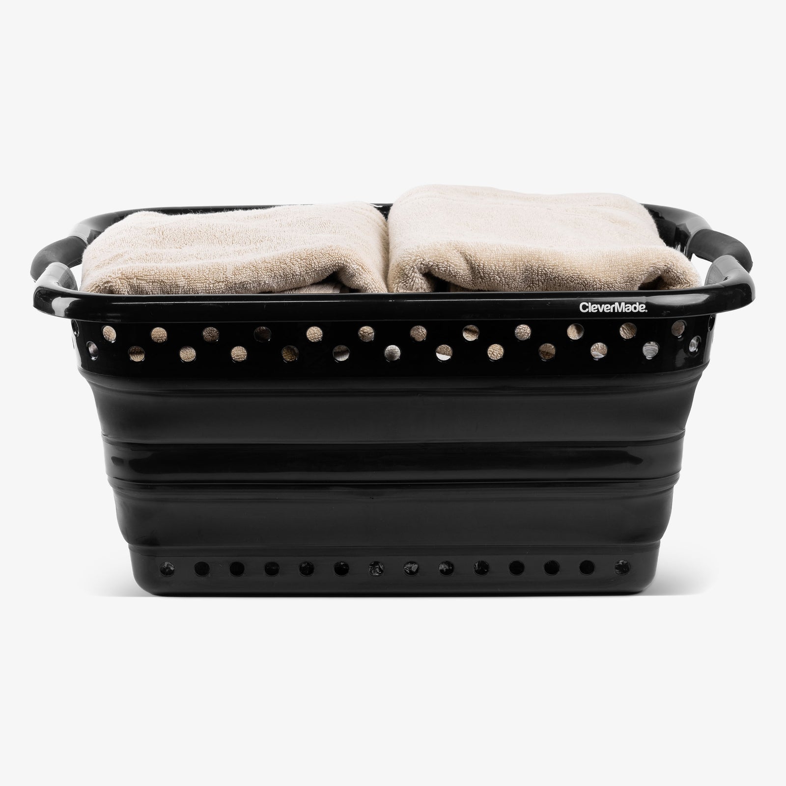 Black collapsible laundry basket with towels inside on a white background