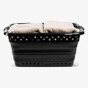 Black collapsible laundry basket with towels inside on a white background