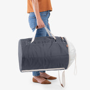 Person holding a gray laundry backpack duffel bag with a white interior on a light background