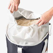 Person looking at laundry backpack duffel bag with towel inside on a white background