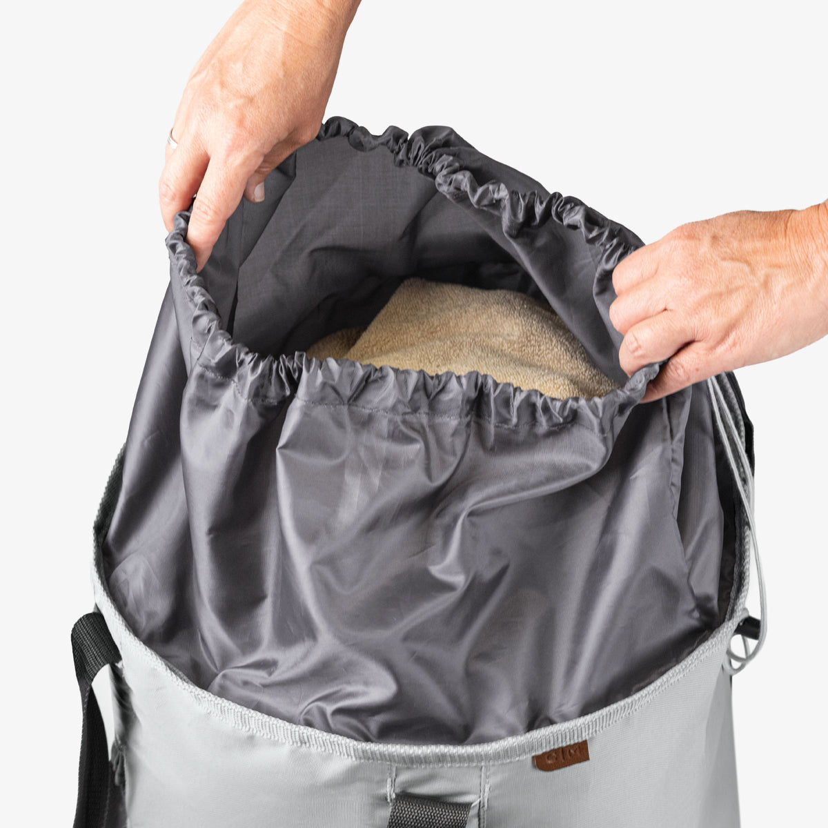 Person looking at laundry backpack duffel bag with towel inside on a white background