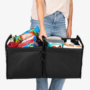 Person holding a black folding trunk caddy with groceries inside on a white background