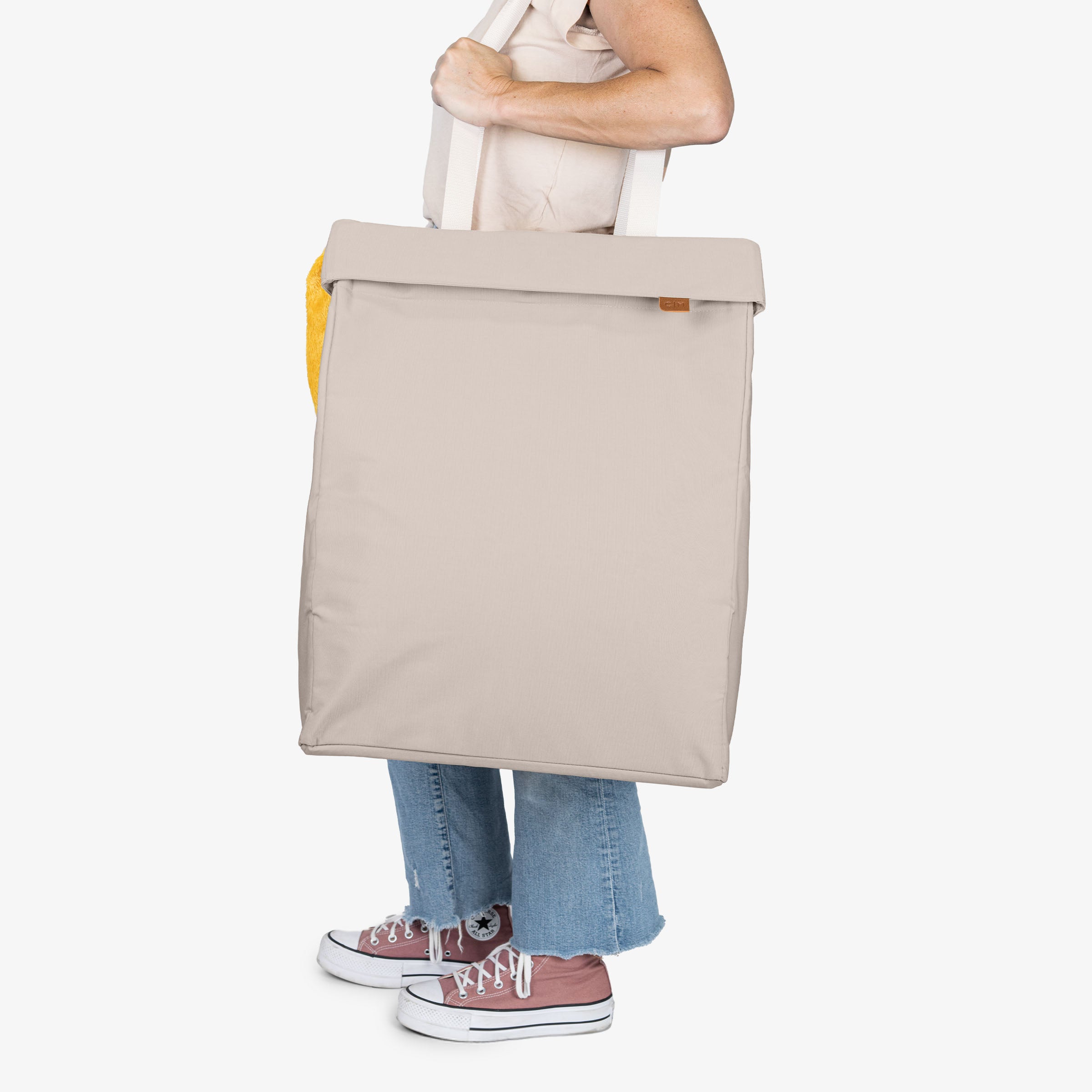Person holding a cream tote bag on a white background