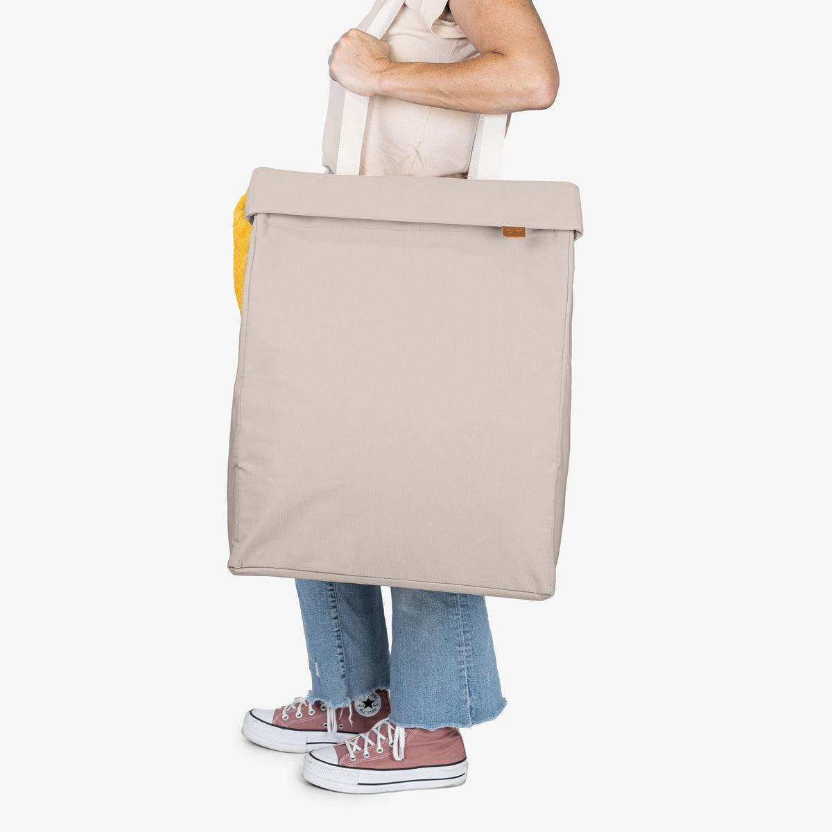 Person holding a cream tote bag on a white background
