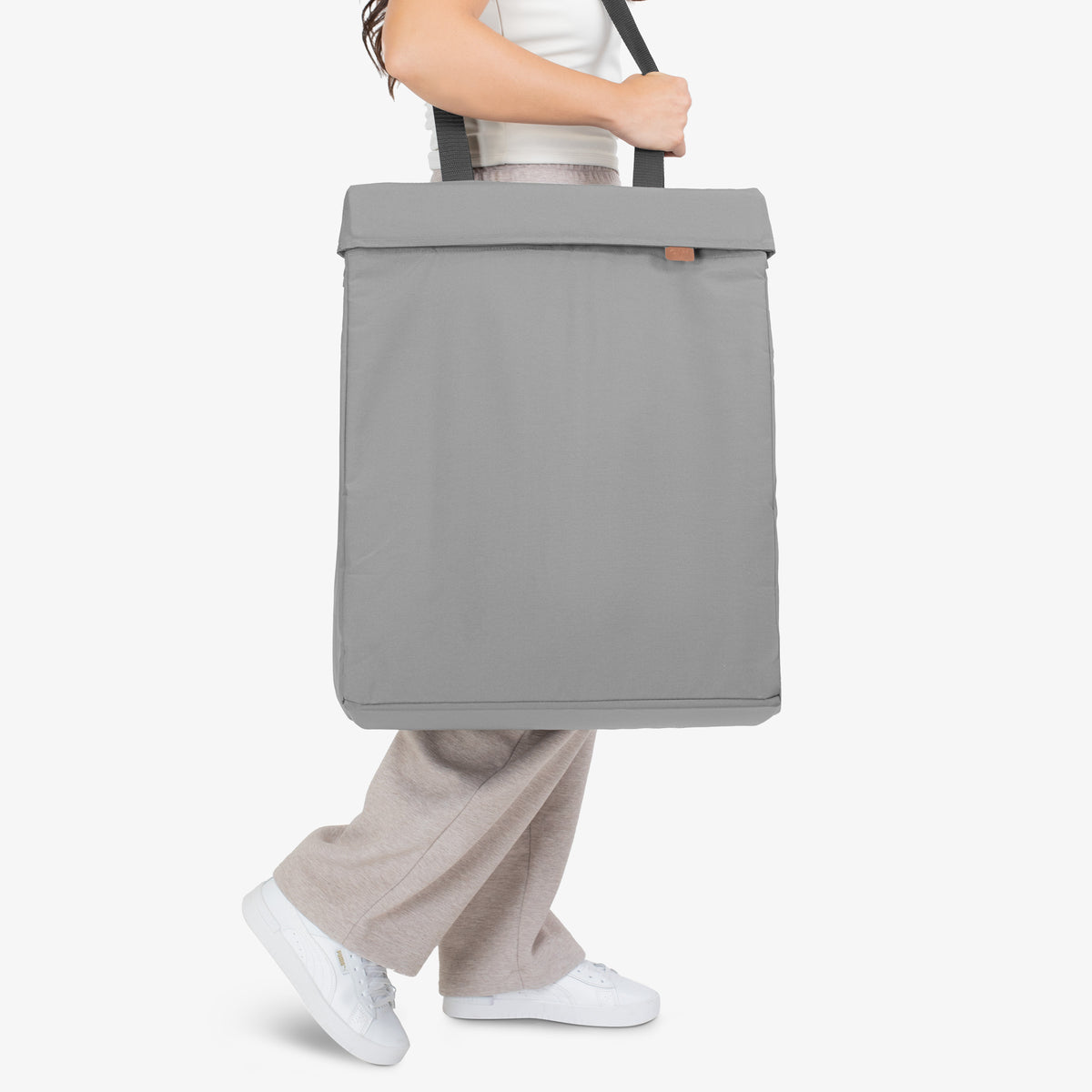 Person holding a gray tote bag on a white background