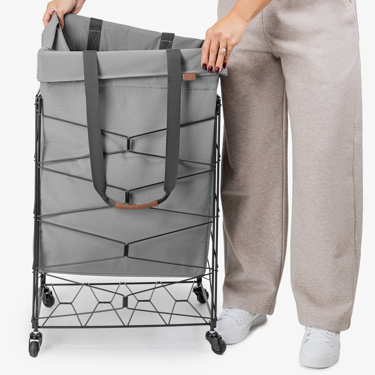 Person holding a gray laundry basket with wheels on a white background