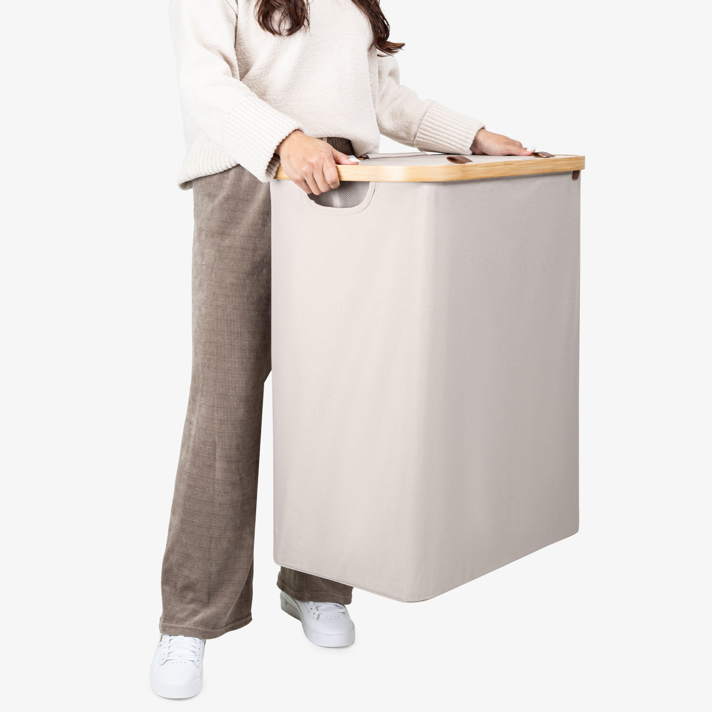 Person holding a beige laundry basket with a wooden handle on a white background