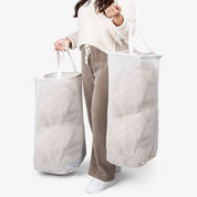 Person holding two large white laundry bags against a white background