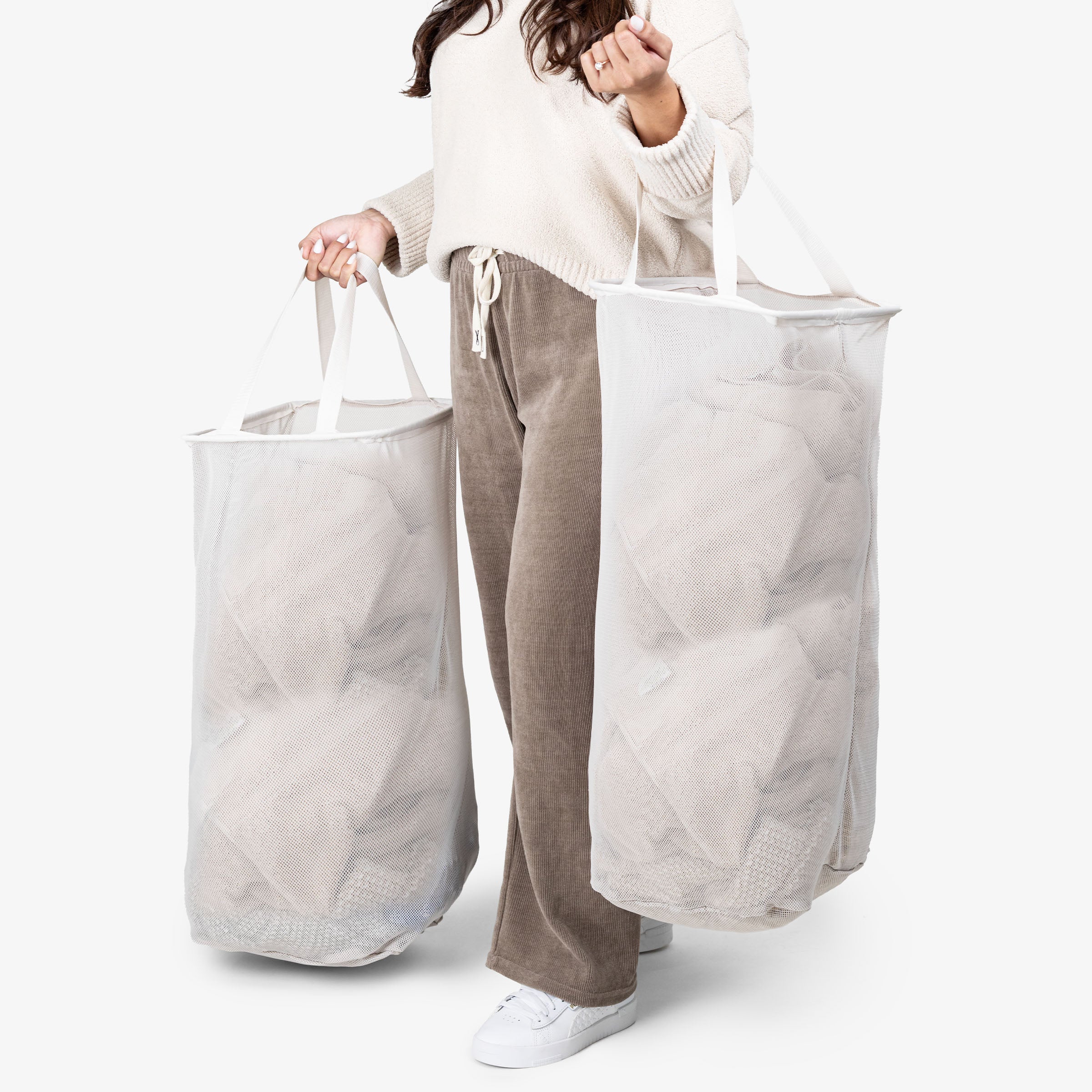Person holding two large white laundry bags against a white background