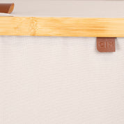 Close-up view of lidded laundry hamper with bamboo accent and a visible brand logo.