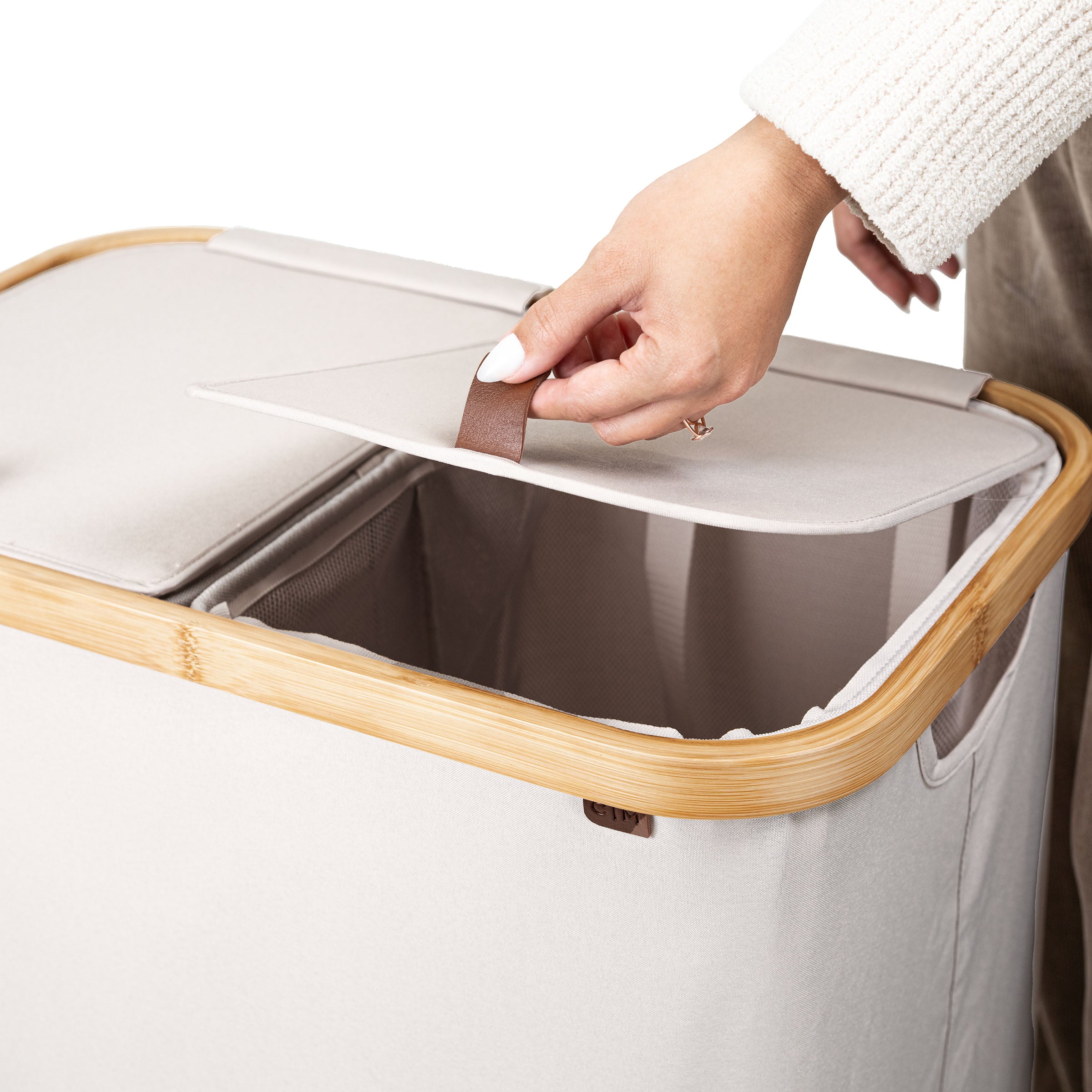 Person opening a beige laundry basket with wooden handle