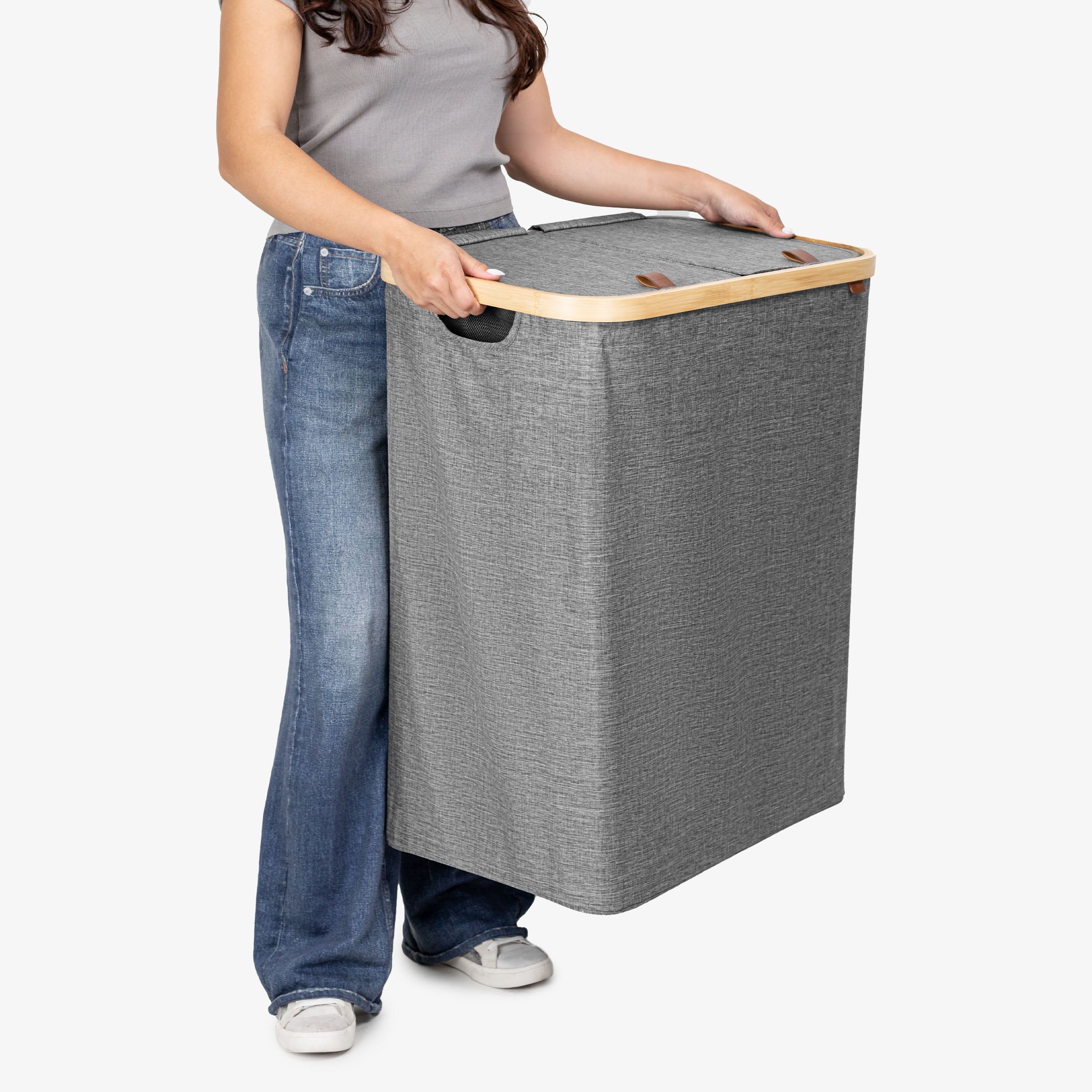 Person holding a gray laundry basket with a wooden handle on a white background