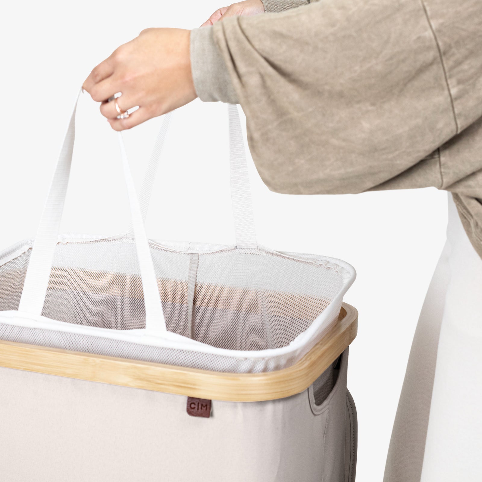 Person holding a mesh laundry basket with a wooden handle on a white background