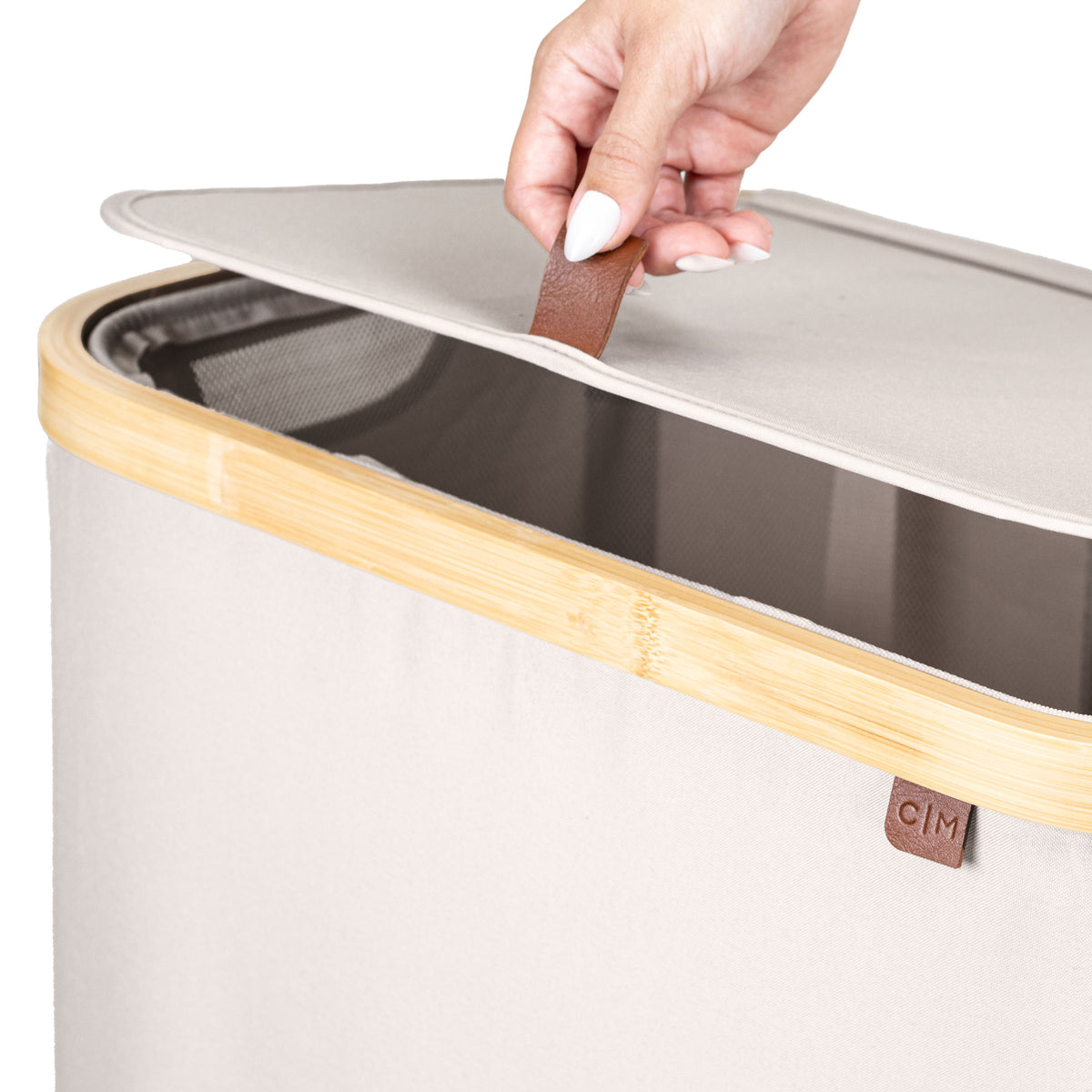 Hand opening a cream laundry hamper
with wooden accents, featuring a visible brand logo.