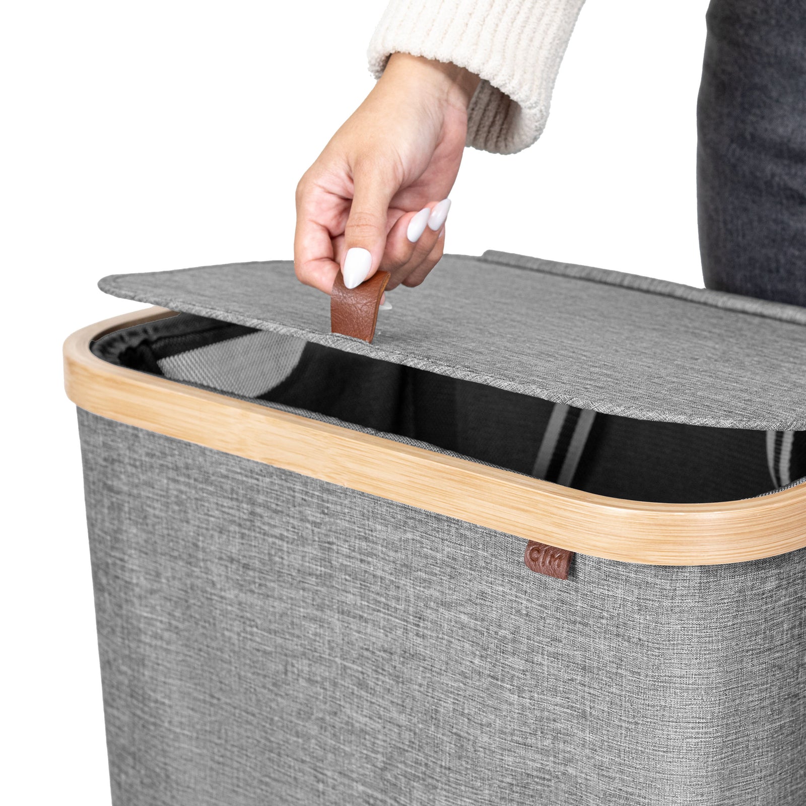 Gray laundry basket with wooden handle and a hand lifting the lid.