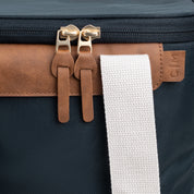 Close up of Malibu collapsible cooler bag with navy blue body, brown leather accents, and white straps with brand label C|M