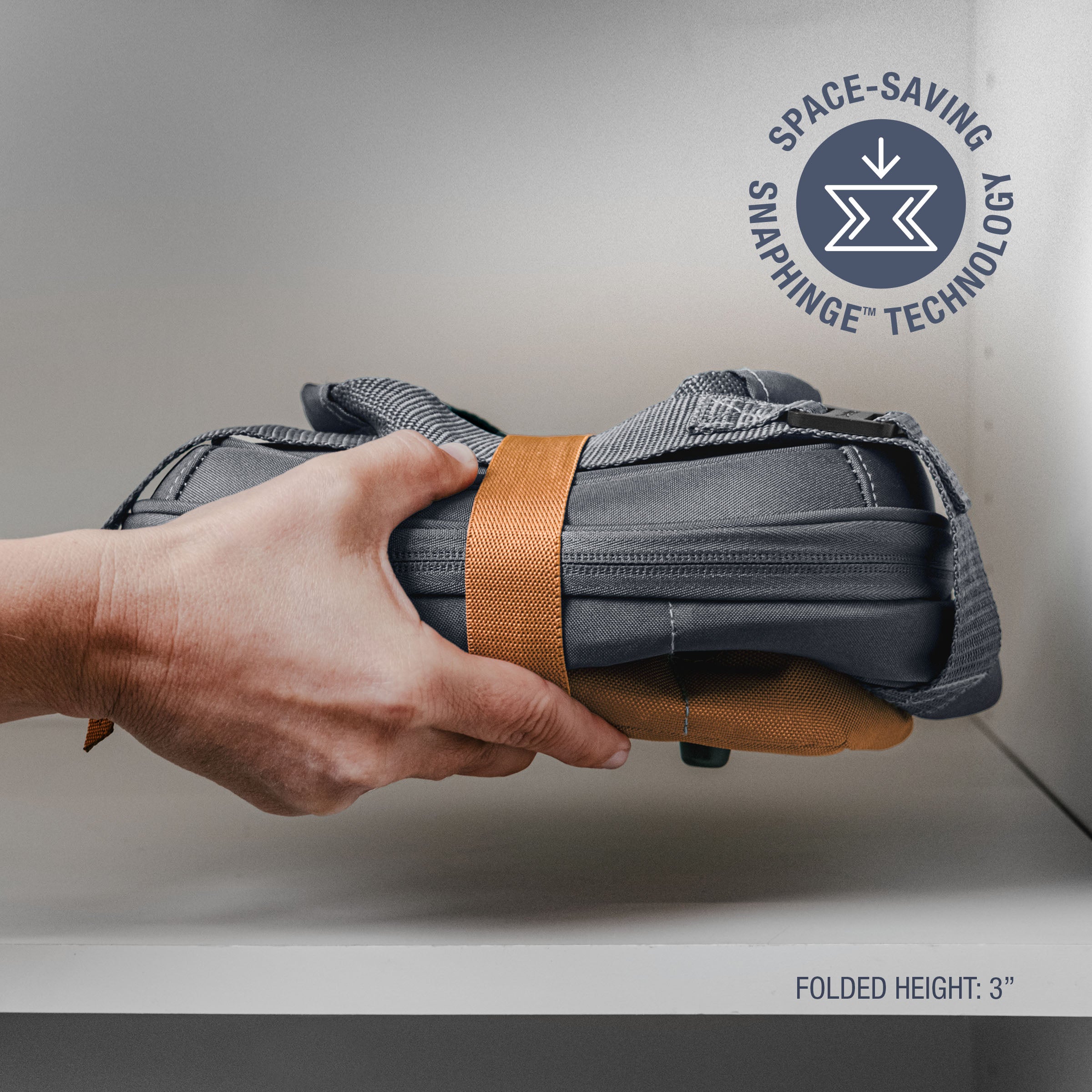 Hand holding a folded gray bag with orange strap, featuring Snap hinge technology logo.