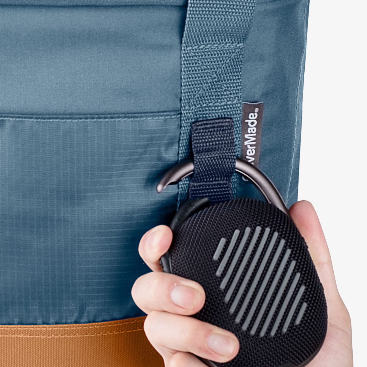 Person holding a black speaker with a blue cooler bag in the background