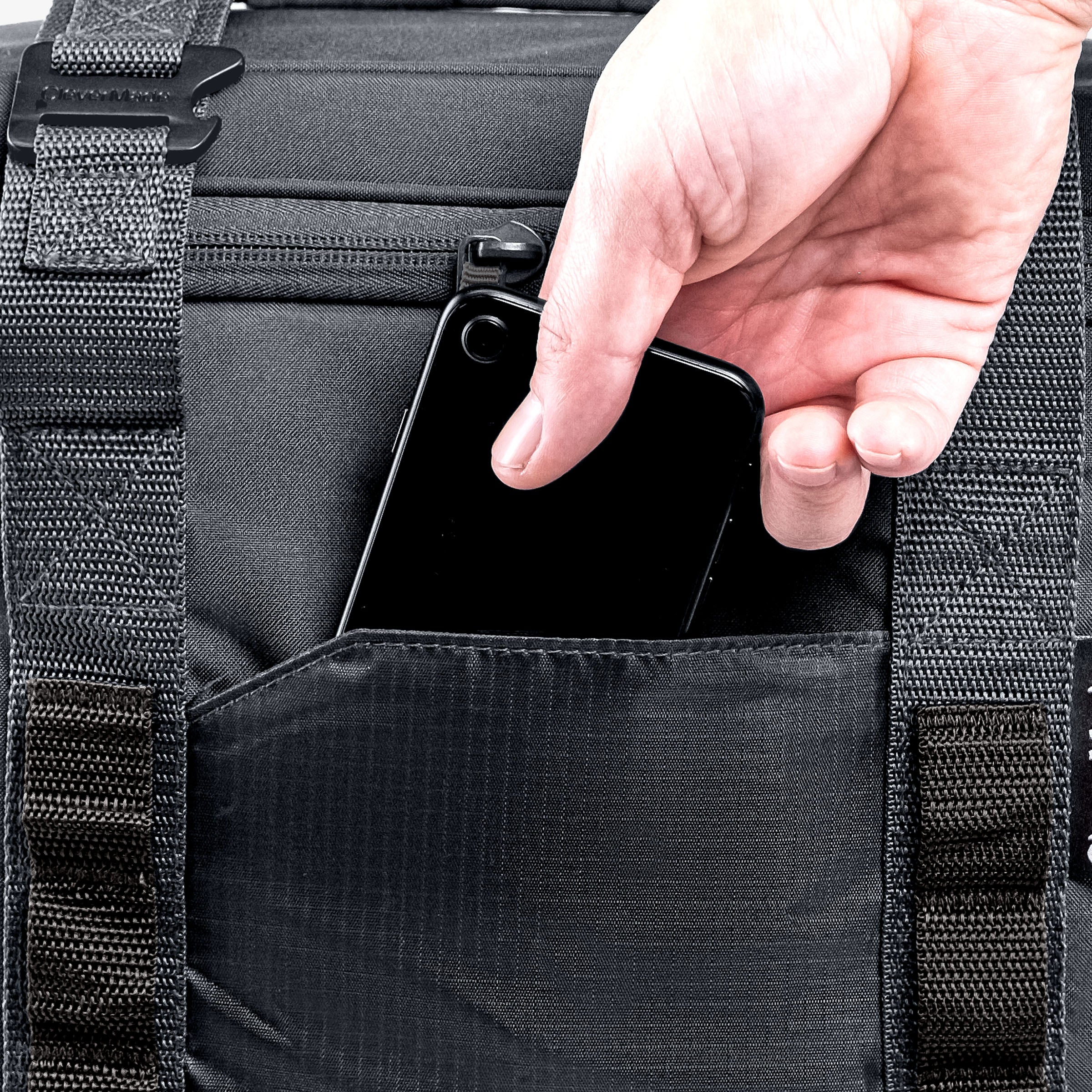 Person placing a smartphone into a black backpack pocket