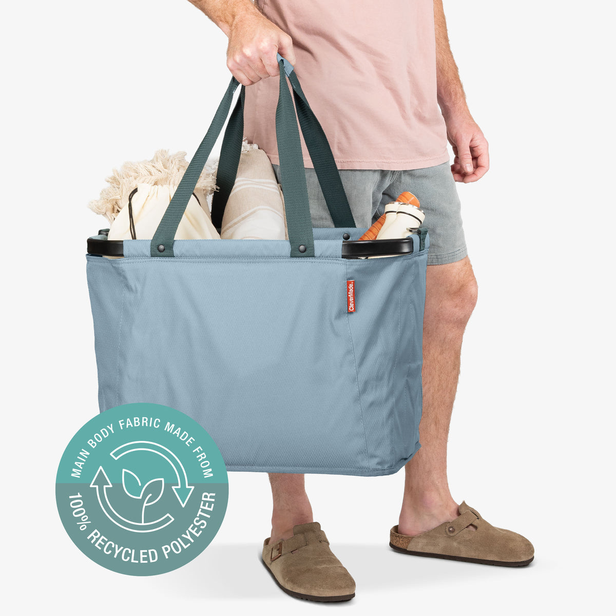 Person holding a blue reusable shopping bag with a visible brand logo on a white background