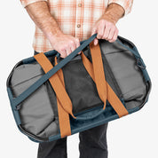 Person holding a gray duffel bag with brown straps on a white background