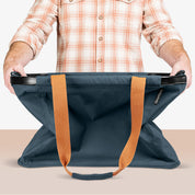 Person holding a blue bag with orange straps on a beige background