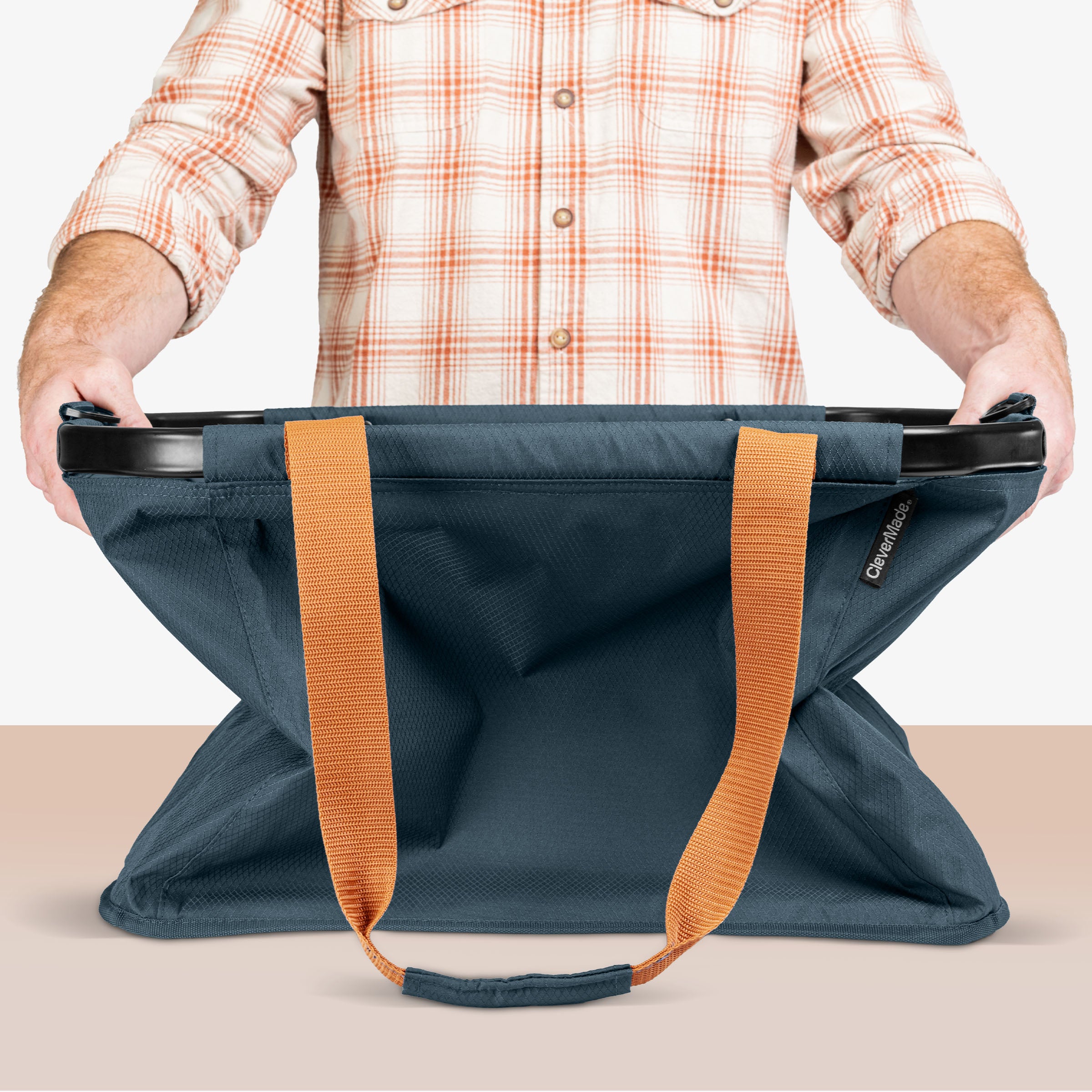 Person holding a blue bag with orange straps on a beige background