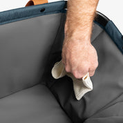 Hand cleaning a gray fabric surface with a white cloth