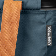 Close-up of a blue bag with an orange strap and CleverMade label.