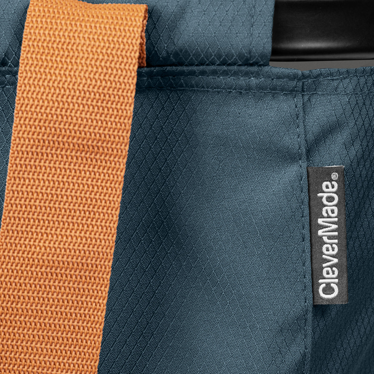 Close-up of a blue bag with an orange strap and CleverMade label.