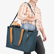 Person carrying a blue tote bag with orange handles on a white background