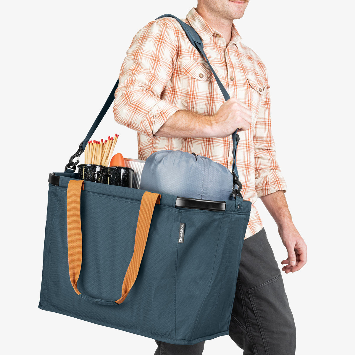 Person carrying a blue tote bag with orange handles on a white background