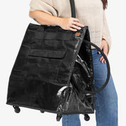 Person holding a large black bag with wheels on a white background