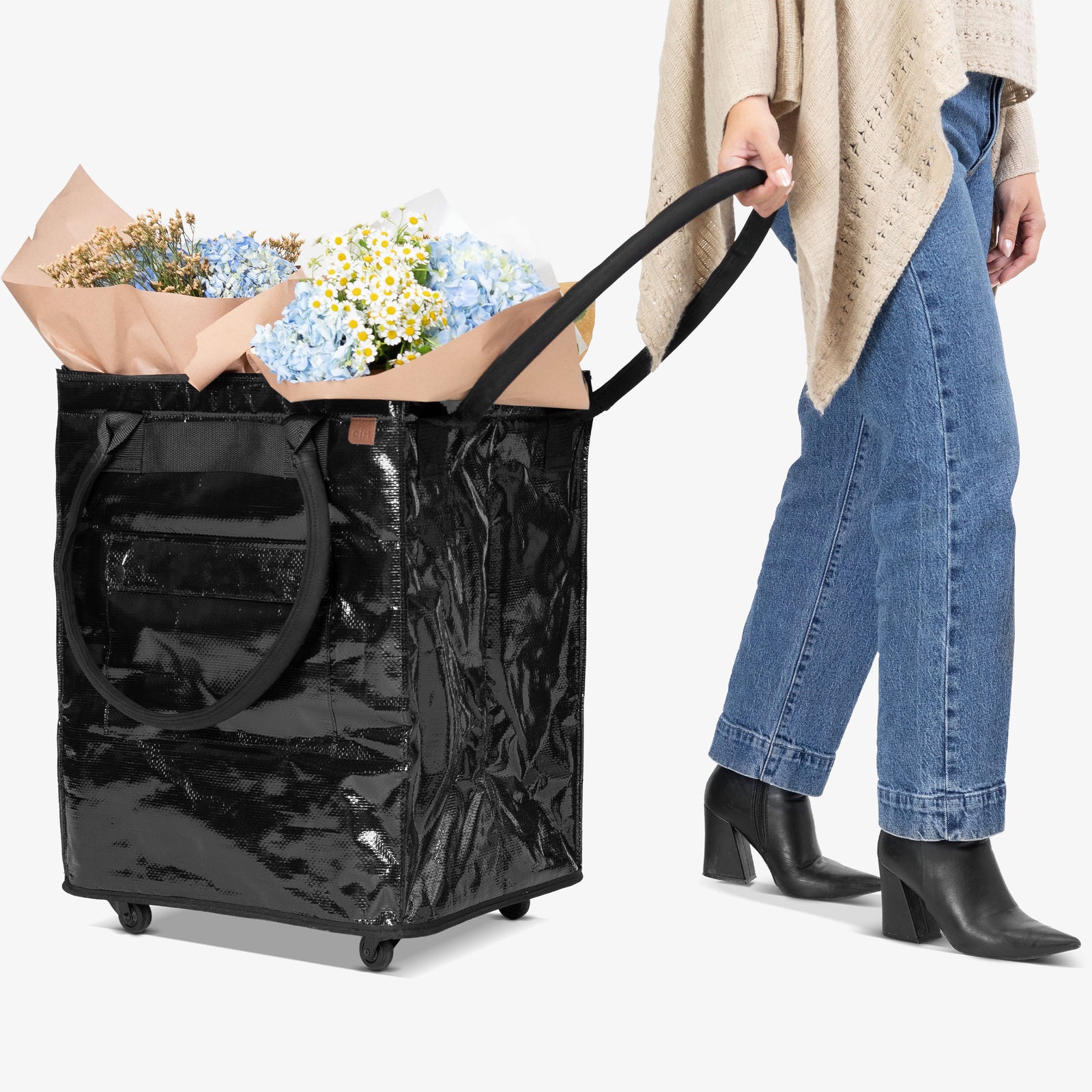 Person pushing a cart with a large floral arrangement through a door.