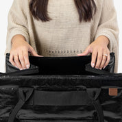 Person holding a black bag with a visible brand logo on a white background