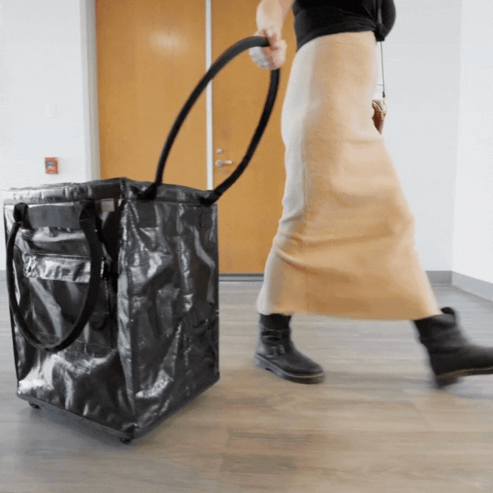 A black rolling tote bag with ergonomic handles and multi-surface wheels.