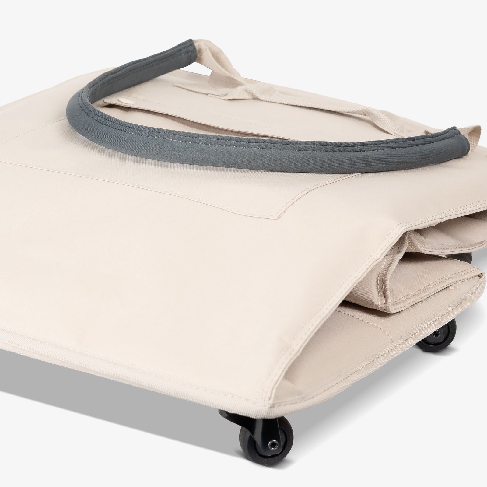 Beige rolling duffel bag with gray handle on a white background