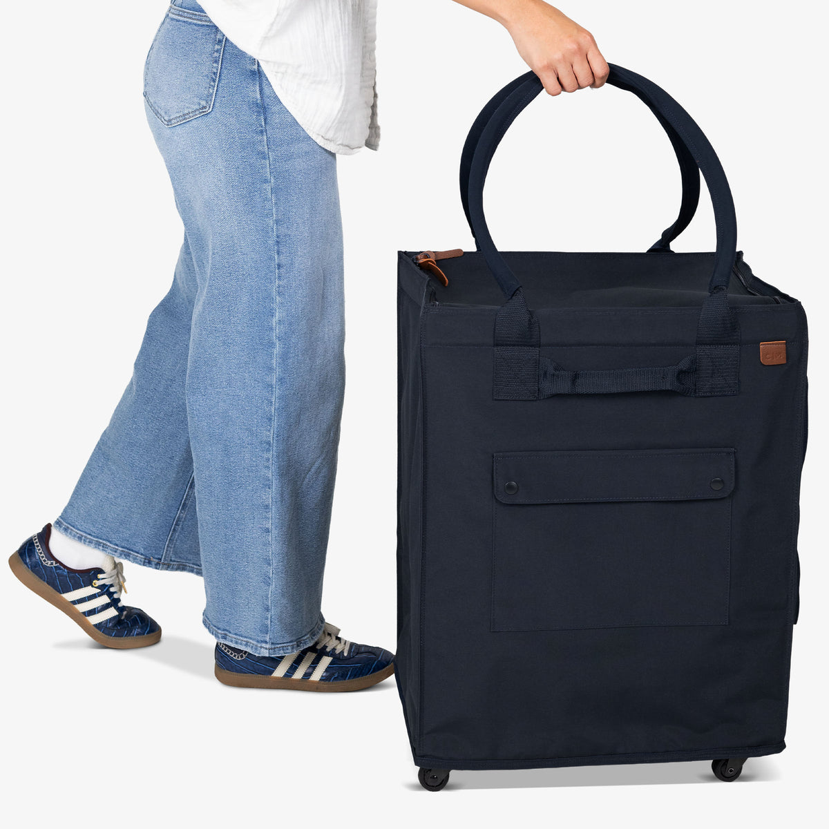 Person holding a navy blue suitcase with a white background