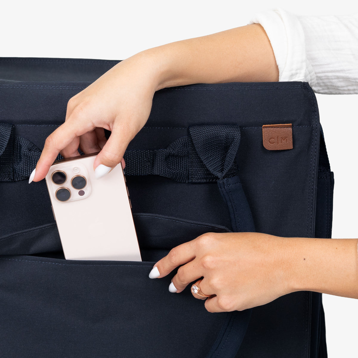 Person placing a phone into a navy blue bag with a visible brand logo.