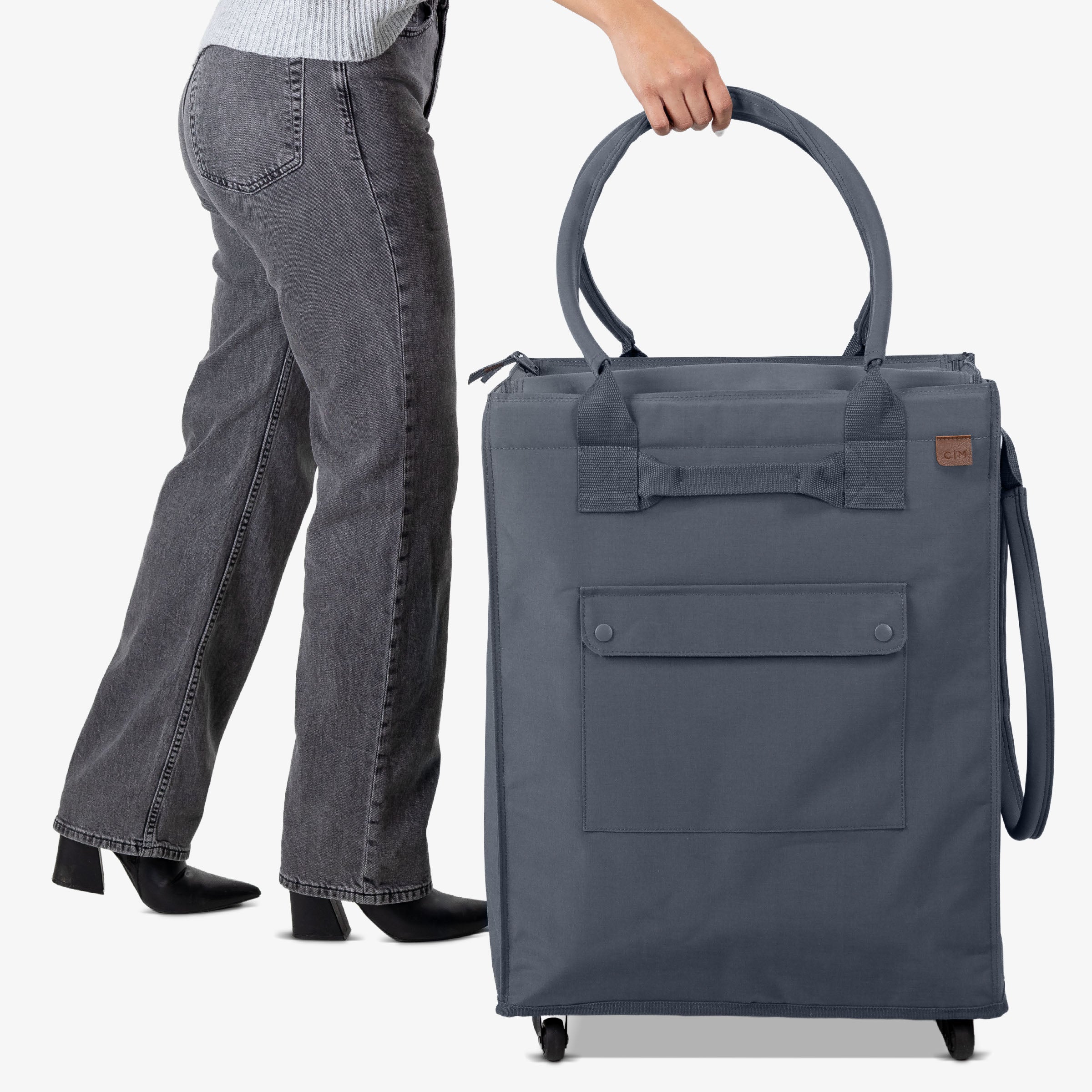Person holding a large gray rolling tote bag on a white background