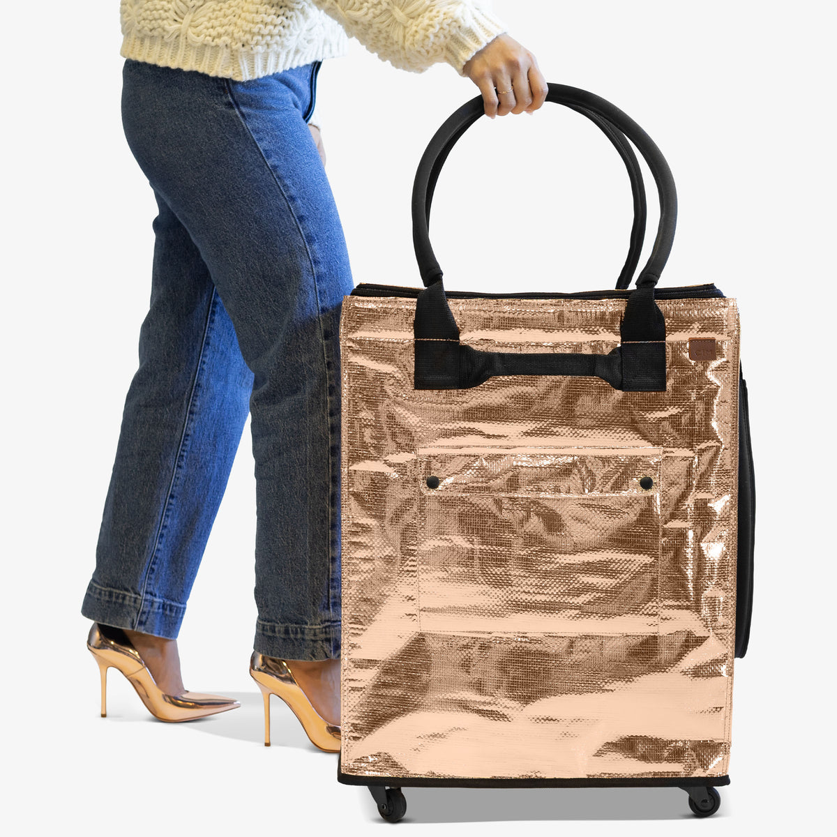 Person holding a metallic shopping bag with wheels on a white background