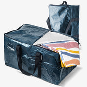 Large blue storage bag with a striped blanket inside on a white background